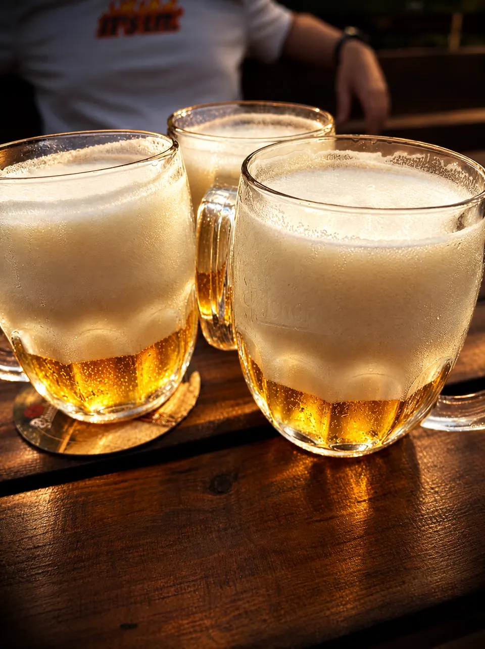 Tři půllitry čepovaného piva s pěnou